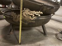 Side view showing dragon cutout design and measurement of fire pit height approximately 18 inches
