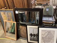 Photo showing two mirrors and four art pieces stacked and leaning against each other with furniture in the background