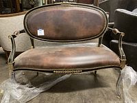 Front view of brown distressed leather two-seater loveseat with black and gold carved frame