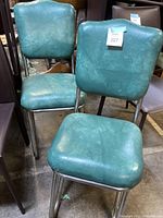Two teal vinyl diner chairs with chrome legs