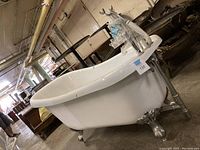 Side angled view of white clawfoot bathtub showing metal claw feet and overall shape.