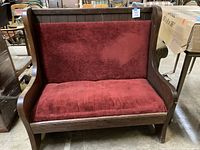 Front view of bench showing red velvet seat and back within dark wood frame