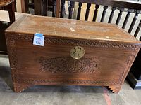 Full front view of the wooden chest showing carved front panel and brass lock.