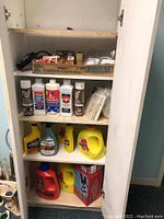 Utility cabinet shelves showing cleaning supplies and utility hardware items.