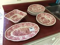 Overview of stacked round plates, large oval platter, and square serving bowls on counter