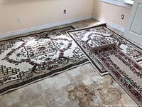 Three rugs displayed on the floor in an empty room showing full view and pattern details.