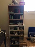 Full view of two wooden shelves filled with sewing supplies and notions.