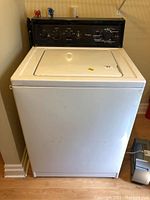 Front view of white top-loading Kenmore washing machine with control panel on top back section.