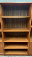 Front view of wooden bookcase showing five shelves with four adjustable shelves and panel back