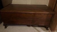 Full front view of the cedar chest showing carved design on front panel and flat top lid.