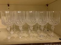 Front view of twenty crystal stemmed glasses arranged in rows on a shelf showing intricate cut pattern and twisted stems.