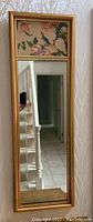 Full view of the mirror showing the gold frame, floral bird panel on top and main mirror below
