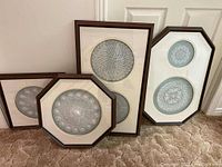 Four different wooden framed lace artworks displayed together on carpet; various shapes and sizes with intricate lace designs visible.