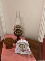Photo showing copper oil lamp and two clocks on wooden surface