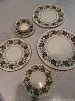 Various pieces of Paragon bone china set including plates of multiple sizes, saucers and tea cups, all decorated with green leaf and pink flower pattern with gold trim.