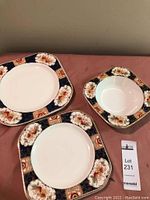 Three pieces: two plates and one bowl showing decorative border with floral pattern in navy blue and rust with gold trim