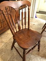 Close-up of side chair showing turned legs, spindled back with carved center splat, and contoured seat.