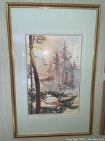 Framed watercolour painting showing tall trees in a misty forest landscape, with a light gold or wood frame.
