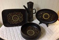 All four pieces of the Denby serving set arranged together on a white surface showcasing their dark base and vibrant circular floral patterns.
