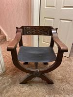 Front view of wooden Renaissance Revival style armchair with leather seat on carpet floor.