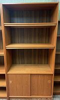 Front view of the wooden bookcase showing three shelves and lower cabinet with sliding doors.
