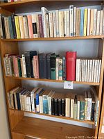 Front view of the wooden bookcase displaying three shelves filled with an assortment of books of different sizes and colors.