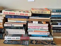 Stack of multiple used books including titles by Alice Munro, Doris Lessing, and others arranged on a flat surface.