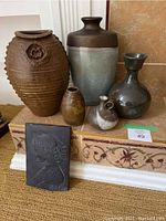 Full lot view showing five ceramic vases and one ceramic plaque arranged on a tiled surface.