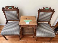 Two wooden chairs with striped blue-gray upholstery flank a small wooden side table; all pieces show some signs of use.