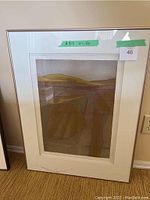 Framed abstract landscape artwork hanging on wall showing geometric shapes and earth tone colors.