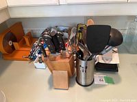 Kitchen counter showing wooden knife block filled with knives, utensil holder with spatulas, and additional kitchen tools.