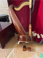 Close-up of the harp-shaped music box highlighting its wooden structure and gold-tone accents.