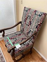 Side angled view of the chair showing carved wooden armrests and detailed upholstery fabric.