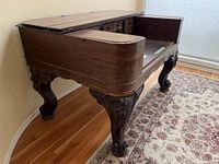 Side view showing curved wood top, hinged panels and ornately carved legs.