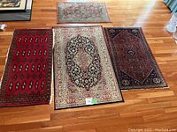 Four small area rugs displayed on hardwood floor, showing various designs and colors.
