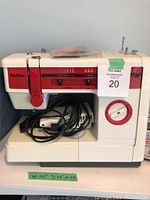 Front view of Brother VX-810 sewing machine showing stitch selector dial, power cord, and black protective cover with red rim.