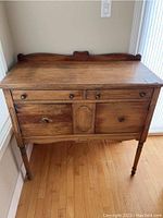Front view of the antique wooden side table with drawers and cabinet.