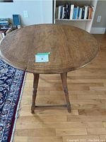 Top front view of the round table showing engraved decorative border pattern and foldable sides.