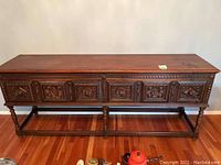 Full frontal view of carved console table on hardwood floor
