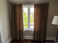 Two brown velvet curtain panels fully lined hanging on a curtain rod, showing the full length and width at a window.