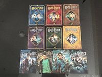 Six Harry Potter Ultimate Edition DVD cases, each numbered 1 to 6 with movie cover art, displayed with character cards featuring main characters from each movie.