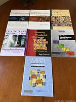 Top view of seven Myers Briggs and temperament psychology books laid flat on a wooden surface showing front covers and titles