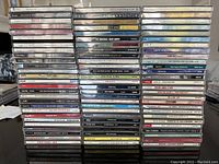 Seven stacks of jewel case CDs arranged on a tabletop showcasing multiple 1980s pop, rock, and new wave titles