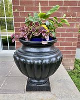 Front view showing planter with inserted flower pot filled with various plants (flowers not included).