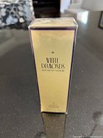 Front view of the sealed gold and purple package of Elizabeth Taylor White Diamonds Eau de Toilette 50 mL.