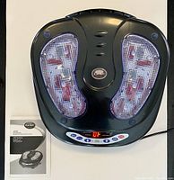 Top view of black iComfort ic0906 foot massager and user manual on white surface.