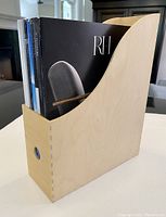 Single natural wood magazine holder filled with magazines showing front and side profile, highlighting dovetail construction and circular cutout handle.