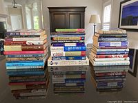 Three stacks of leadership and business books displayed on a reflective surface, showing variety and volume of the lot.