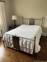 Full view of metal bed frame with white textured bedspread, showing headboard and footboard details.