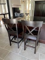 Two dark wooden X-back bar chairs positioned by a bar counter.
